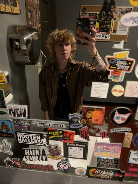 A man standing in front of a refrigerator full of stickers.