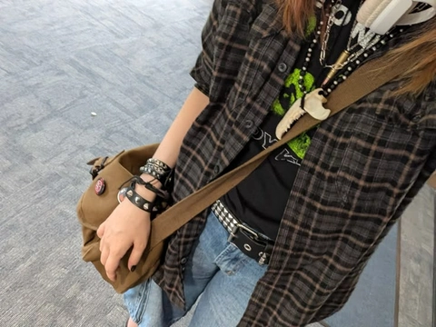A woman wearing a black and white checkered shirt and blue jeans.