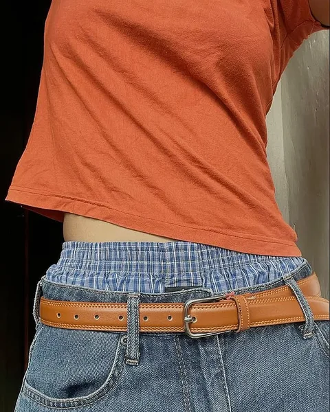 A woman wearing a red shirt and a brown belt.