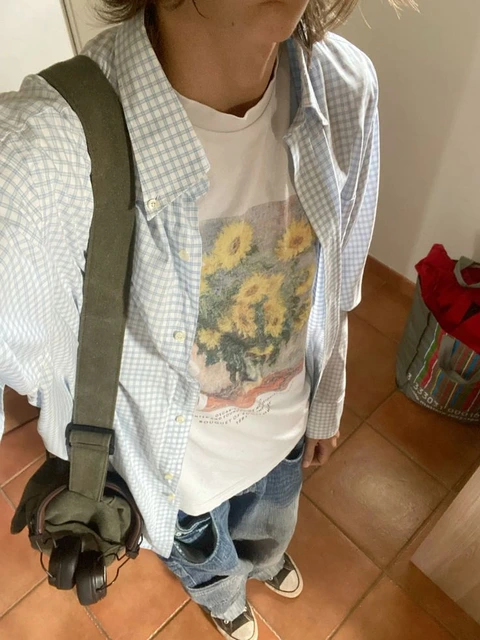 A woman standing in front of a mirror wearing a shirt with a picture of a flower on it.