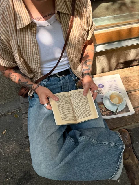 A woman sitting on a bench reading a book.