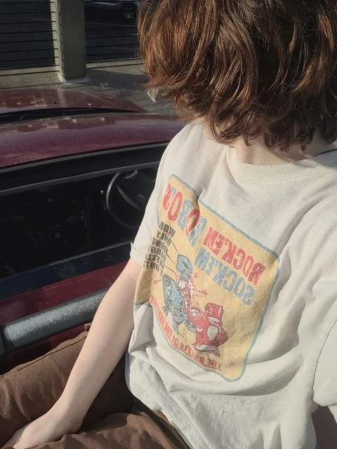A person sitting on the back of a car with their head in the window.