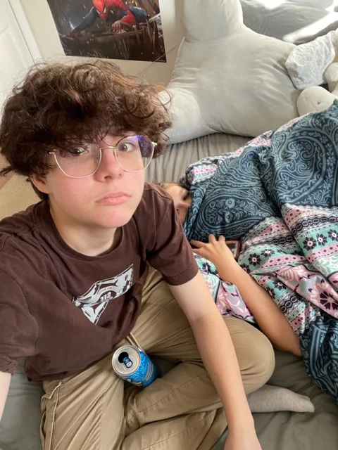 A young man with glasses sitting on a couch next to a woman.