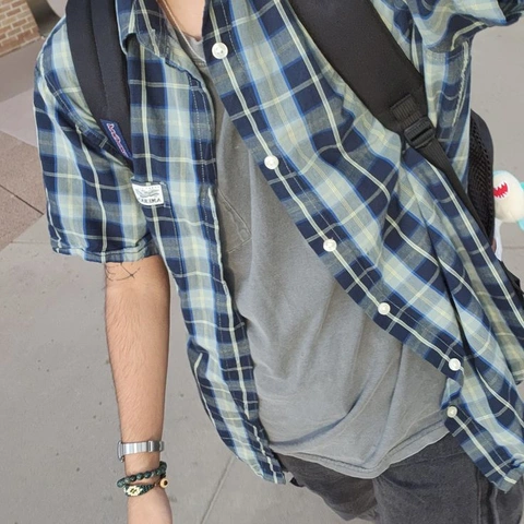 A man wearing a blue and white plaid shirt with a backpack.