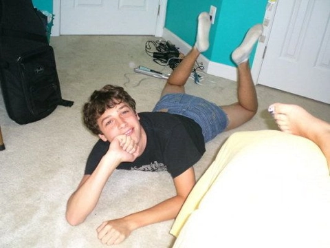 A young man laying on the floor with his feet up.