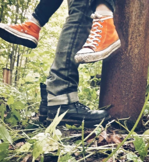 A pair of people standing next to a tree in the woods.