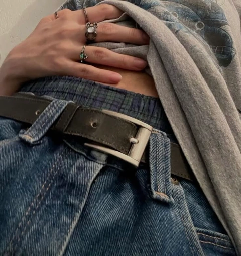 A woman wearing a pair of jeans and a t-shirt with rings on her hands.
