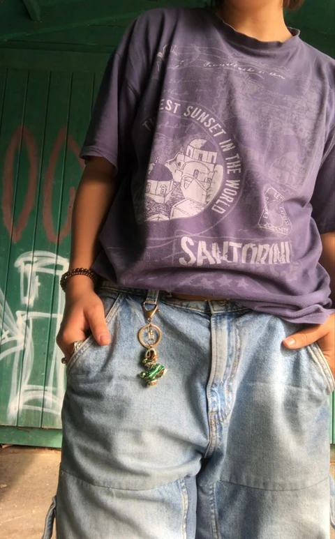 A man wearing a purple shirt and jeans standing in front of a green door.