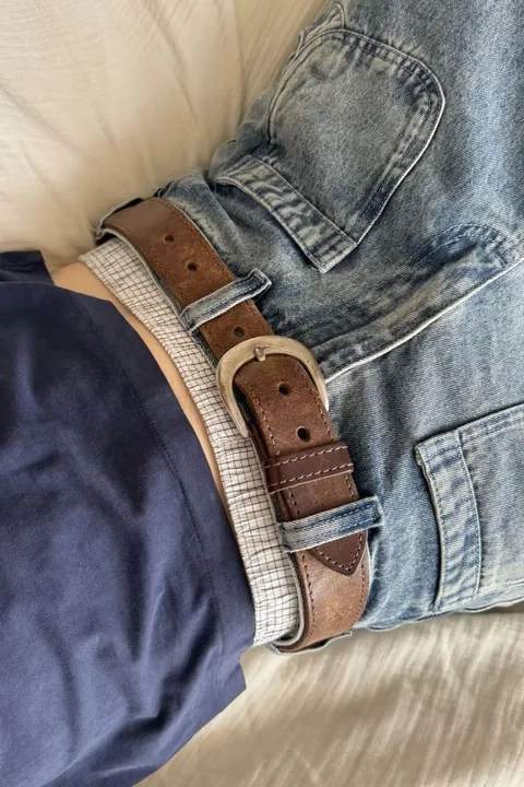 A close up of a person wearing a pair of jeans and a belt.
