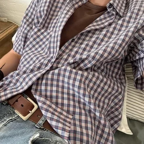 A man wearing a brown and white checkered shirt and jeans.