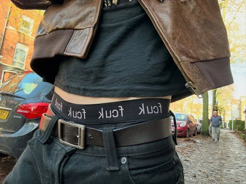 A man wearing a leather jacket and a belt with the words "just for you" written on it.