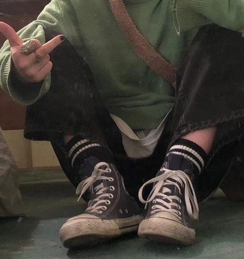 A person sitting on a bench with their feet up in the air.