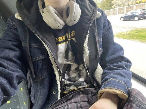 A person wearing headphones sitting in the back seat of a car.