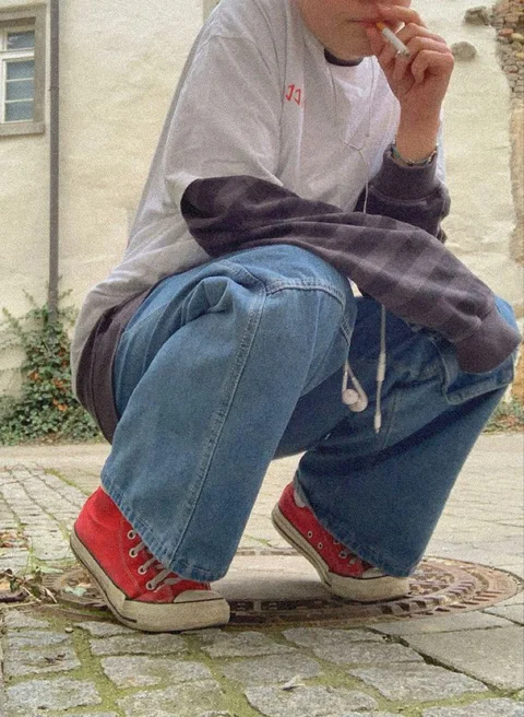 A man sitting on the ground smoking a cigarette.