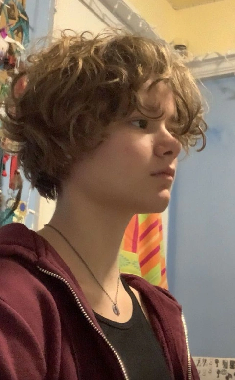 A mannequin with curly hair in front of a colorful wall.