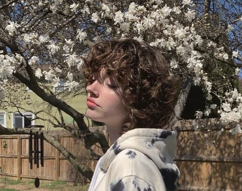 A woman standing in front of a tree with white flowers.