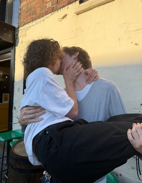 A couple of people that are kissing in front of a building.