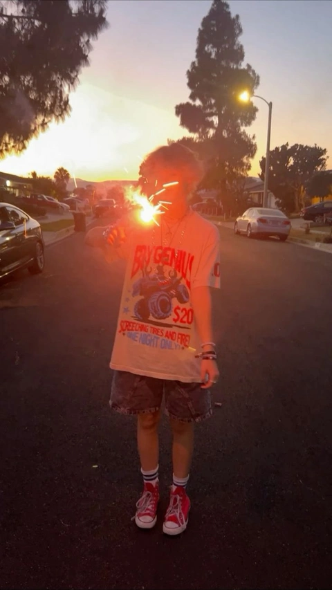 A man standing in the middle of a parking lot holding a fire.