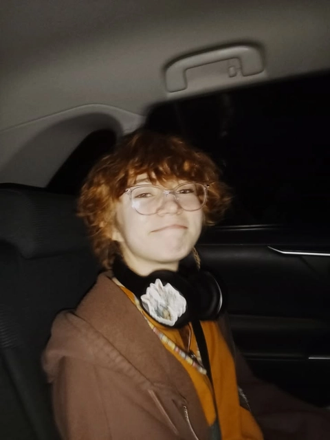 A man with glasses and a wig sitting in a car.