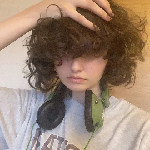 A young boy with curly hair wearing headphones.