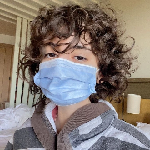 A woman with curly hair wearing a face mask.