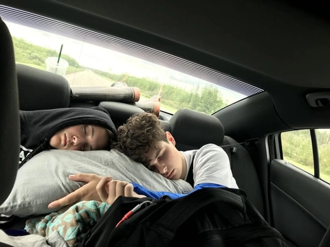 A couple of people laying on top of a car seat.