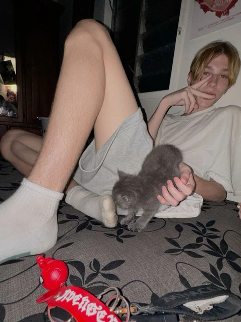A man laying on a bed with a cat in his lap.