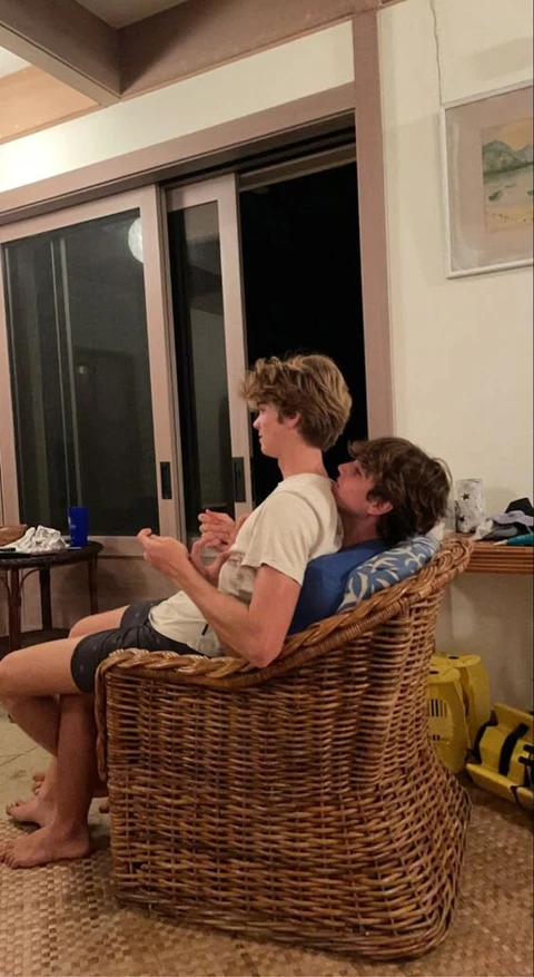 A couple of people sitting on top of a wicker chair.