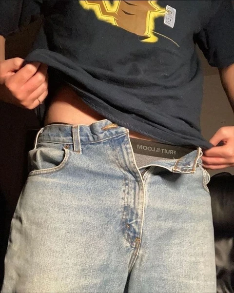 A pair of jeans with a black shirt on top of them.