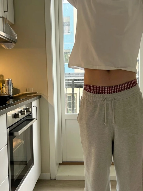 A person standing in front of a window in a kitchen.