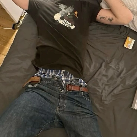 A man wearing a black shirt and jeans with a brown belt.