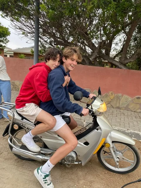 A group of young men riding on the back of a motorcycle.