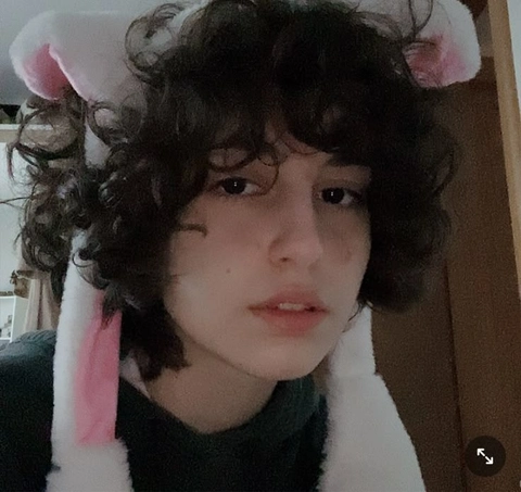 A young boy with curly hair wearing bunny ears.