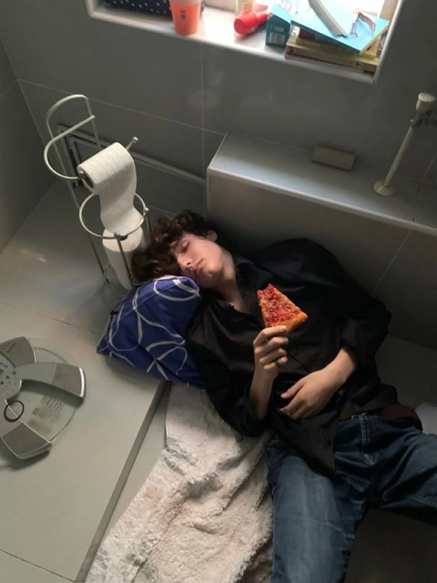 A man and a woman laying on a bed eating pizza.