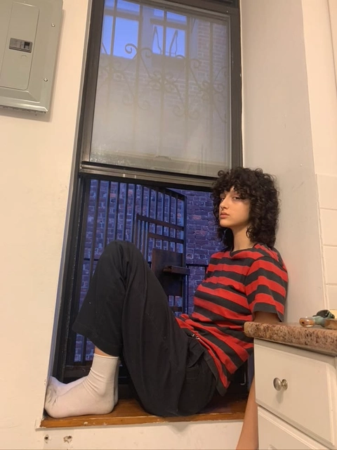 A man sitting on a window sill in a bathroom.