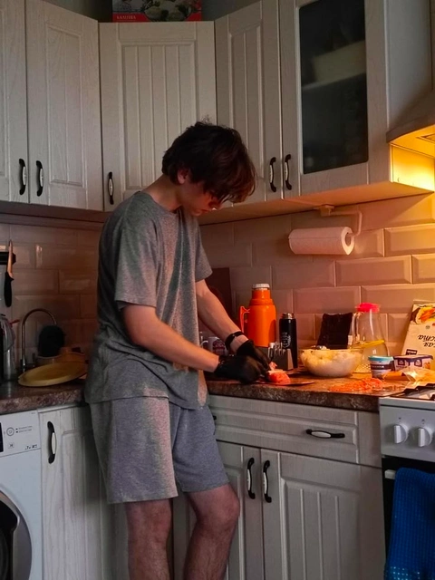 A man standing in a kitchen preparing food on a counter.