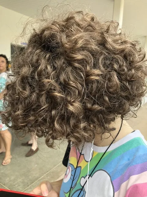 A woman with curly hair standing in front of a mirror.