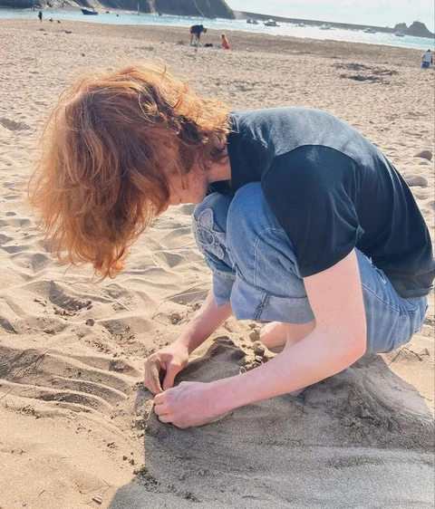 A man and a woman are building a sand castle on the beach.