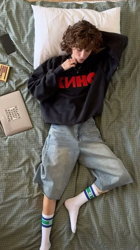 A man laying on top of a bed next to a pillow.