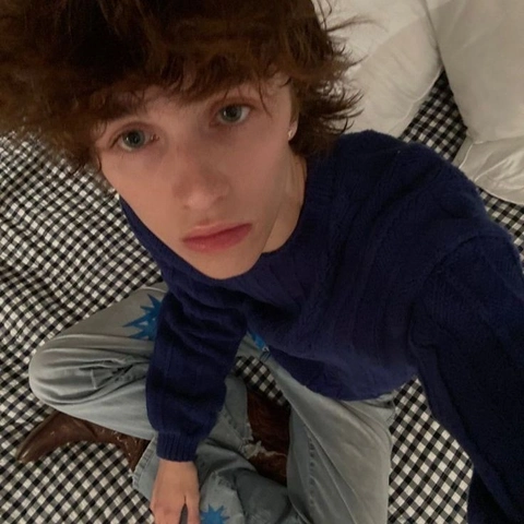 A young girl with curly hair sitting on a bed.