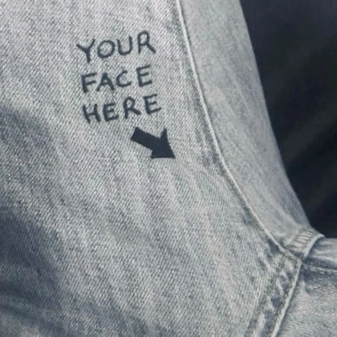 A pair of jeans with the words your face here written on them.