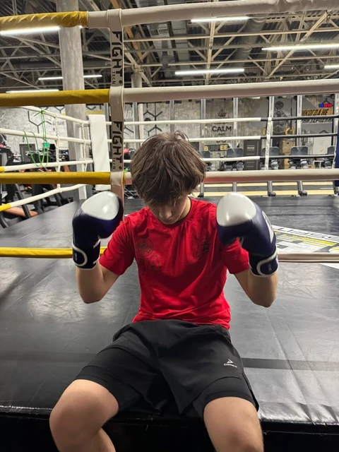 A young boy wearing boxing gloves in a boxing ring.