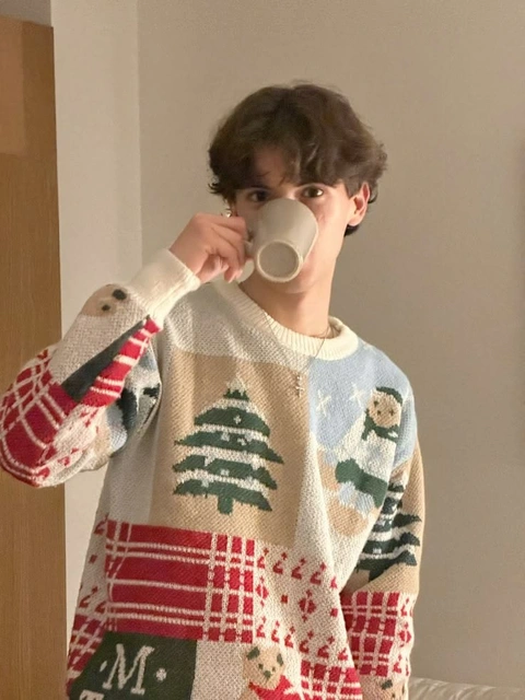 A man in a sweater drinking from a cup.