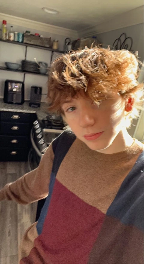 A young boy with curly hair standing in a room.