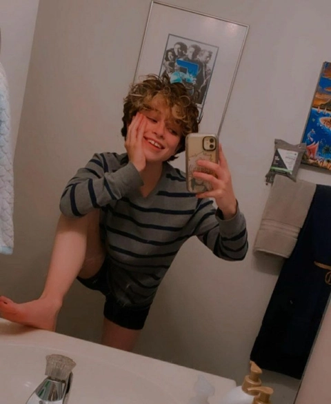 A young boy taking a picture of himself in a bathroom mirror.