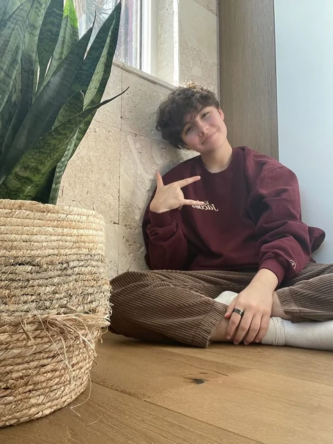 A woman sitting on the floor next to a plant.