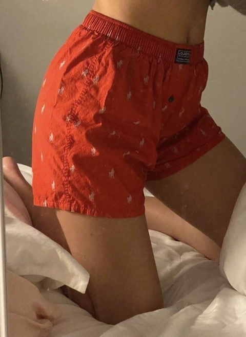 A woman wearing a pair of red shorts on a bed.