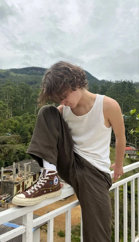 A man sitting on top of a white railing.