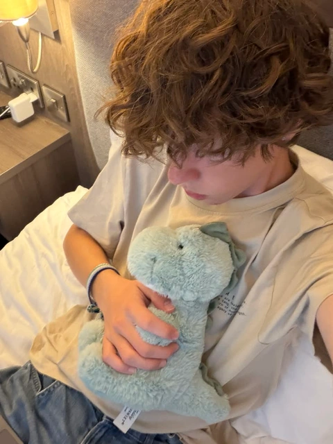A young man holding a teddy bear in his hands.