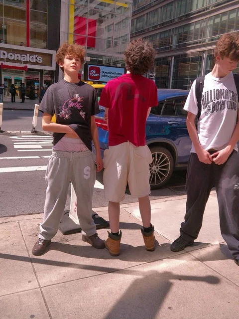 A group of young men standing next to each other on a sidewalk.